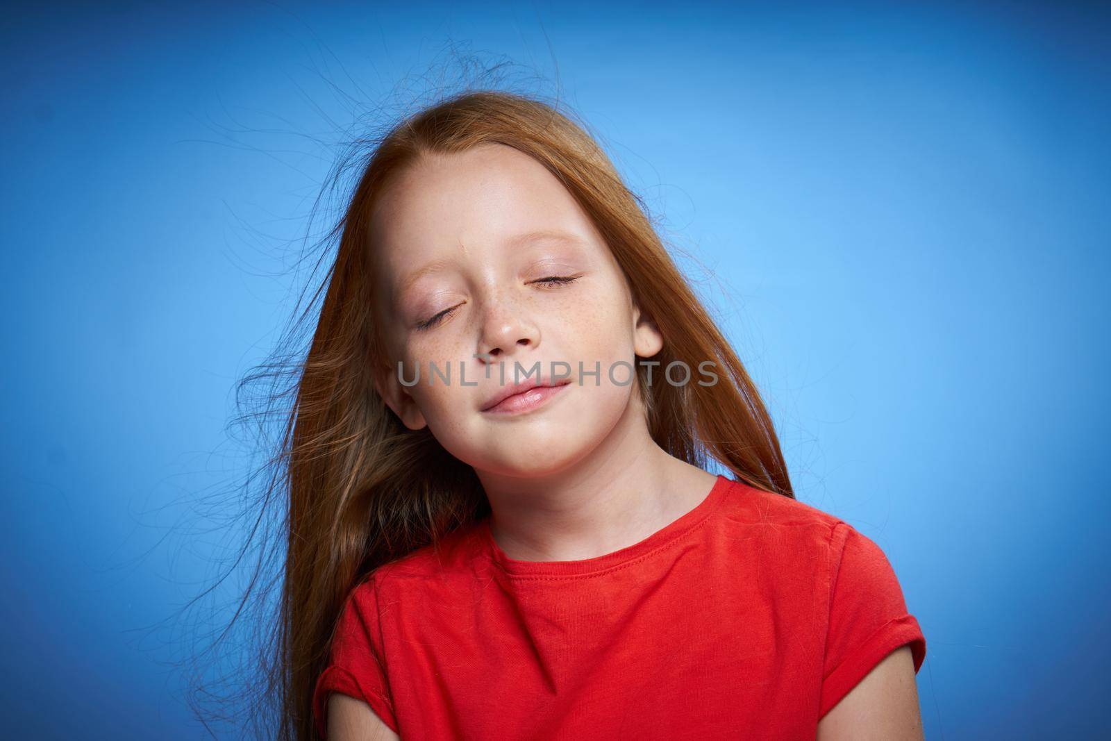 cheerful cute red-haired girl childhood blue background. High quality photo