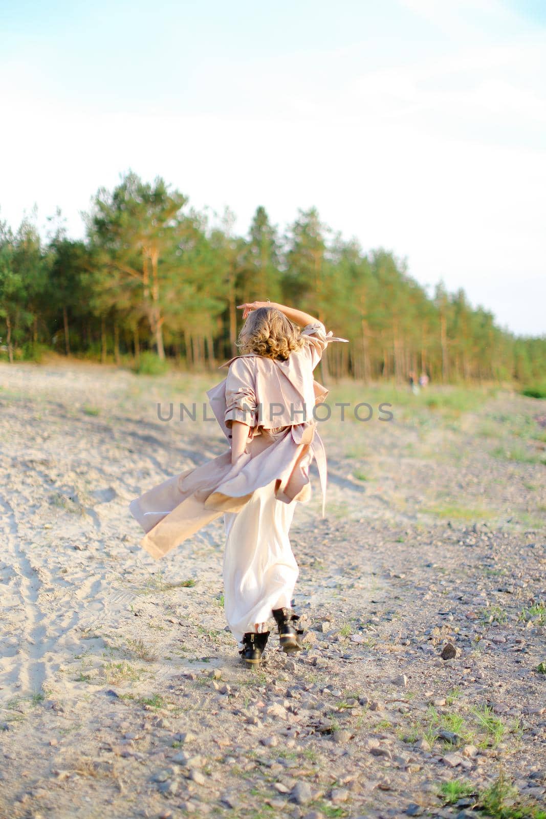 Young blonde woman turning around on sand with trees in background. by sisterspro