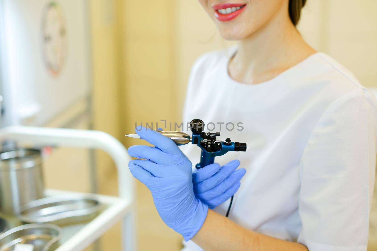 Close up cosmetologist hands in latex gloves keeping microblading device at beauty salon. by sisterspro