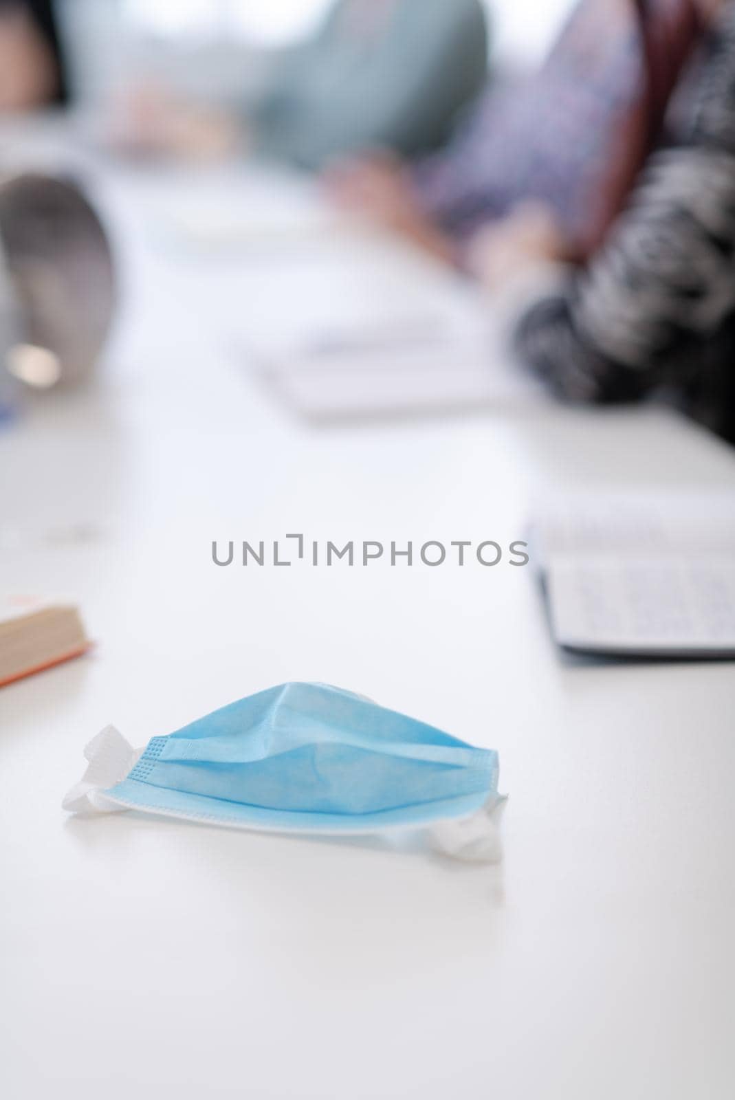 Closeup of protective medical face mask  at desk on business meeting  coronavirus pandemic new normal time