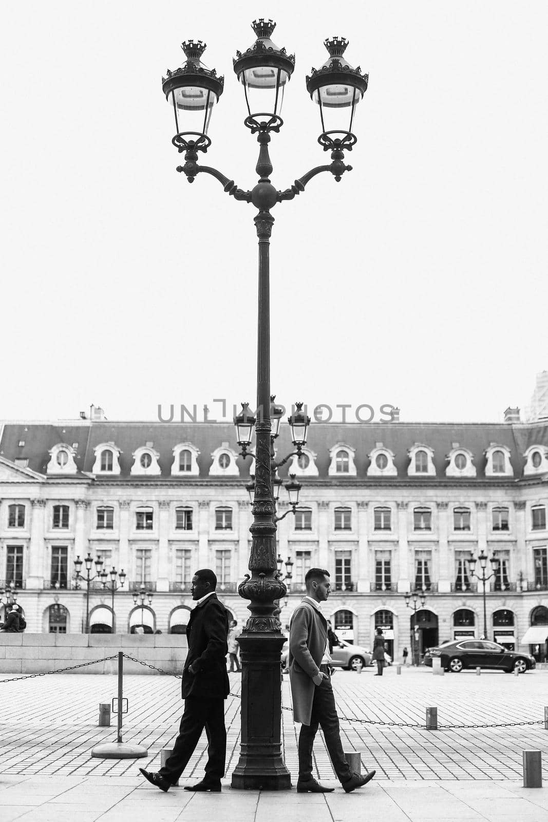 Black and white photo of afro american and caucasian men standing near street lantern in city. by sisterspro