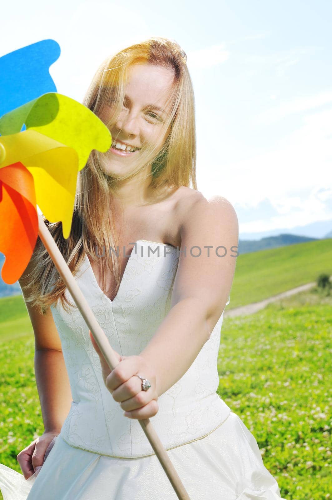 happy young beautiful bride after wedding ceremony event have fun outdoor on meadow at sunset with windmill toy and representing smart energy 