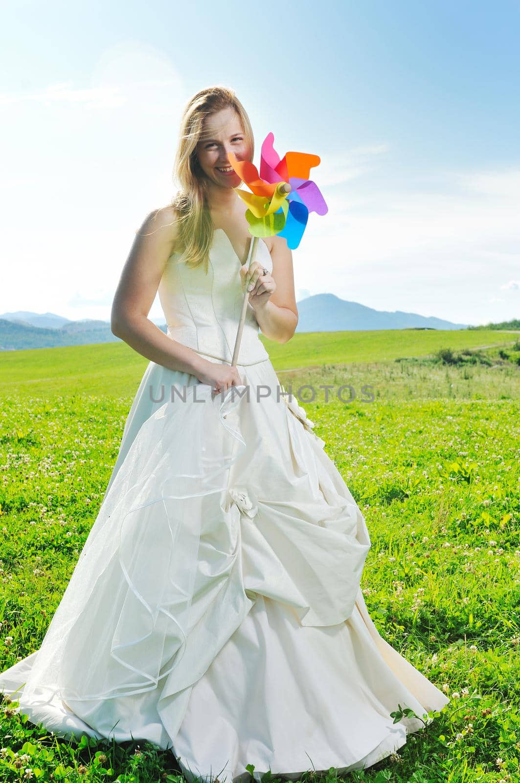 happy young beautiful bride after wedding ceremony event have fun outdoor on meadow at sunset with windmill toy and representing smart energy 