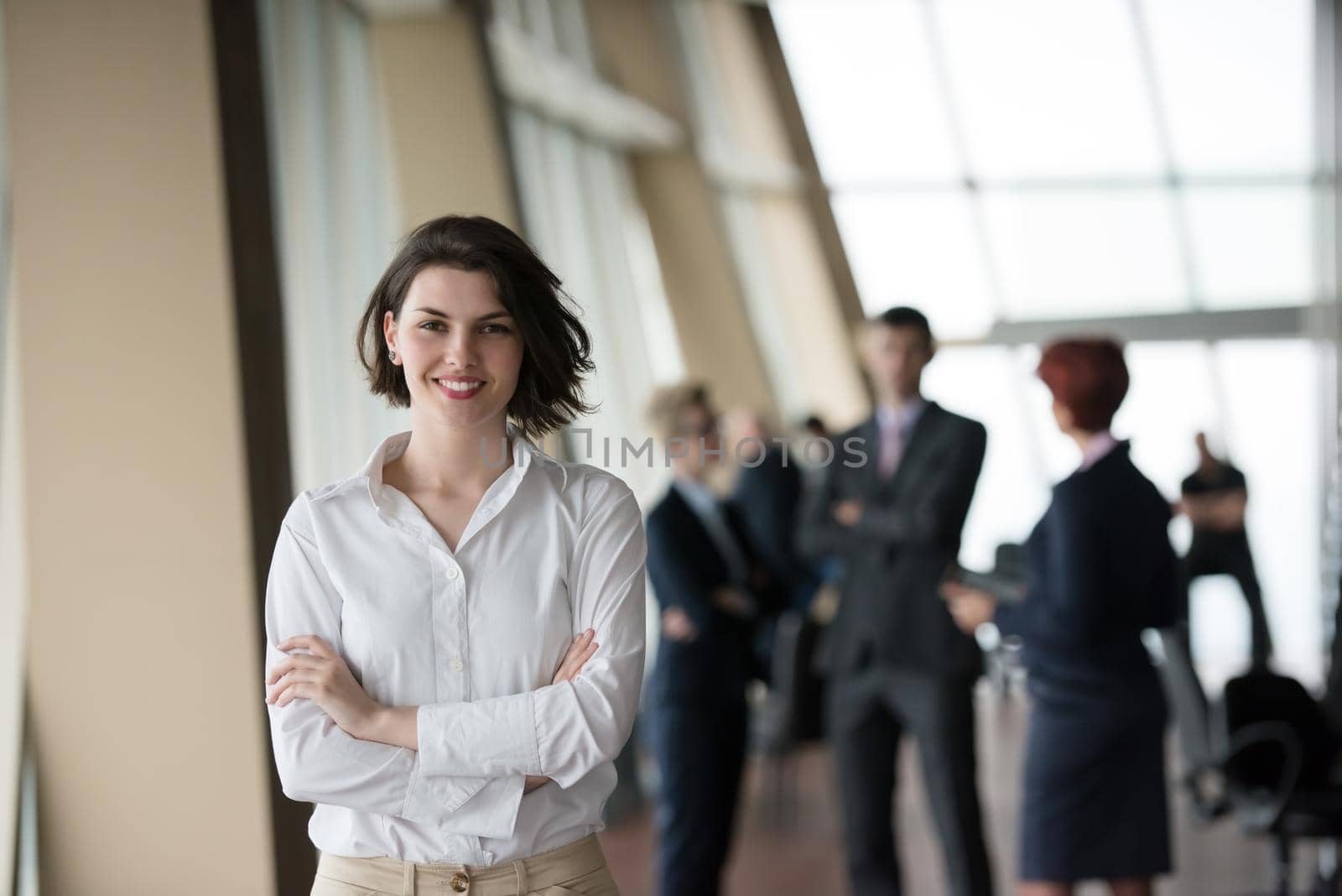 happy young business woman in front her team blured in background. Group of young business people at modern bright  startup office interior.