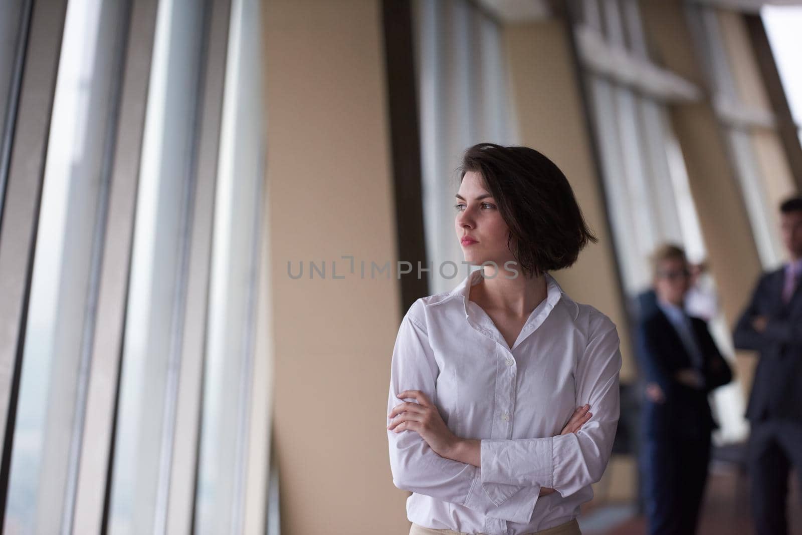 Smilling young business woman in front her team blured in background. Group of young business people. Modern bright  startup office interior.