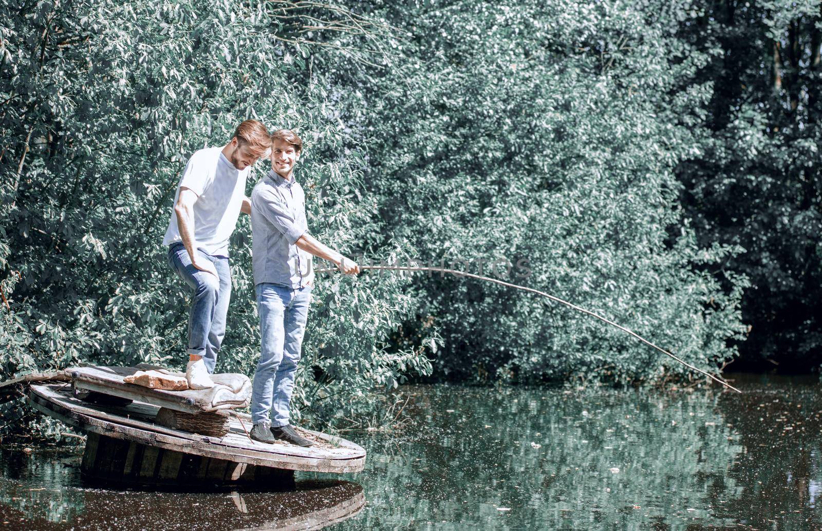 two friends are fishing on the lake in the early morning . lifestyle