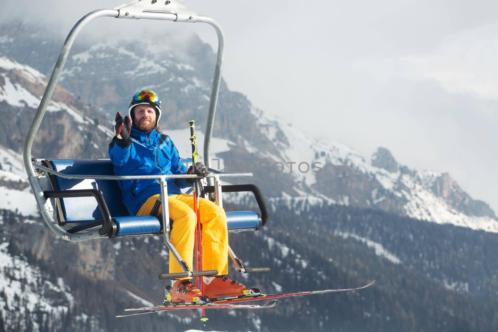 Skier man on ski chair lift Dolomites Italy in wintertime beautiful alps winter mountains and ski slope Cortina d'Ampezzo Col Gallina