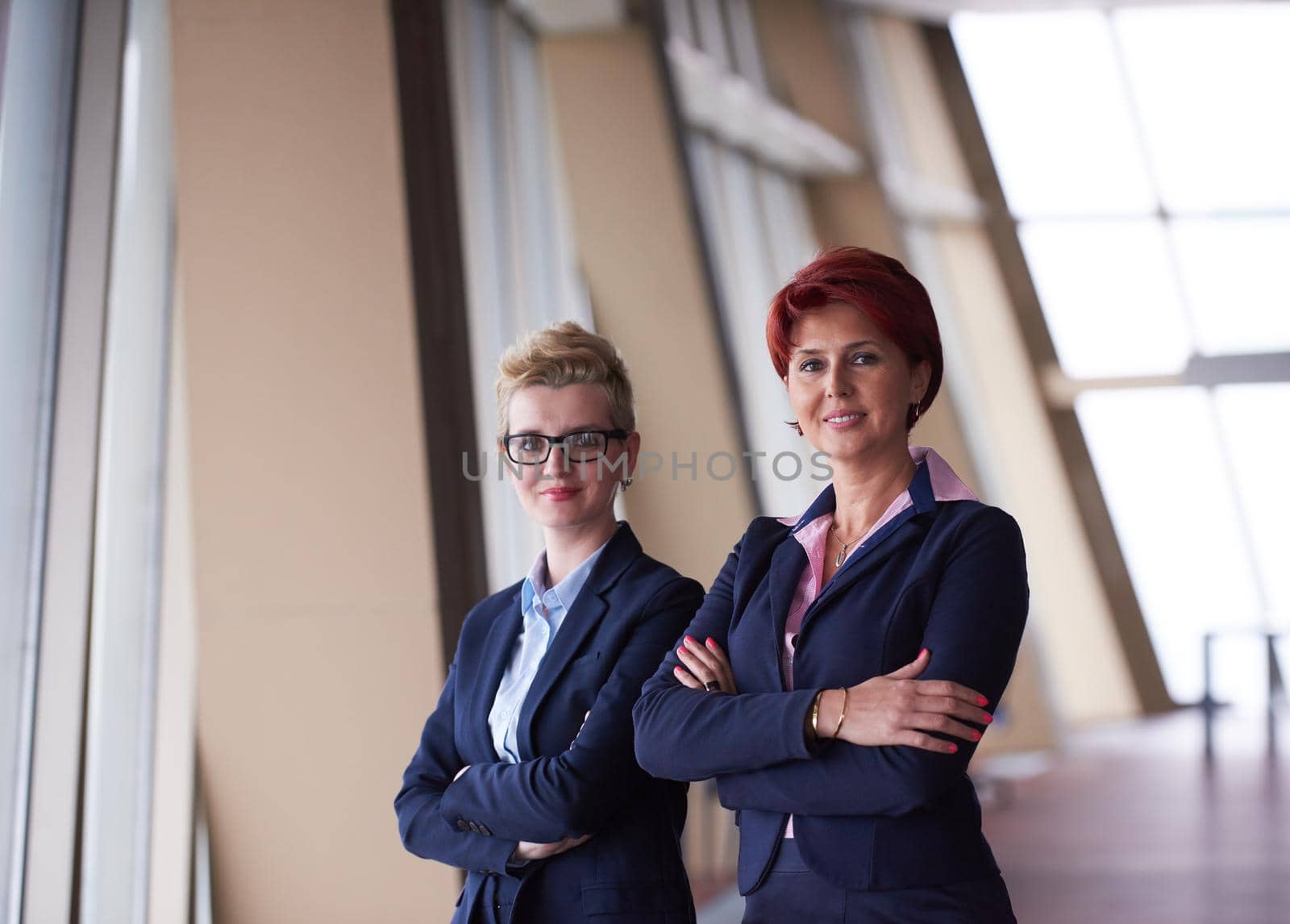 portrait  of two corporate business woman at modern bright office interior standing in group as team