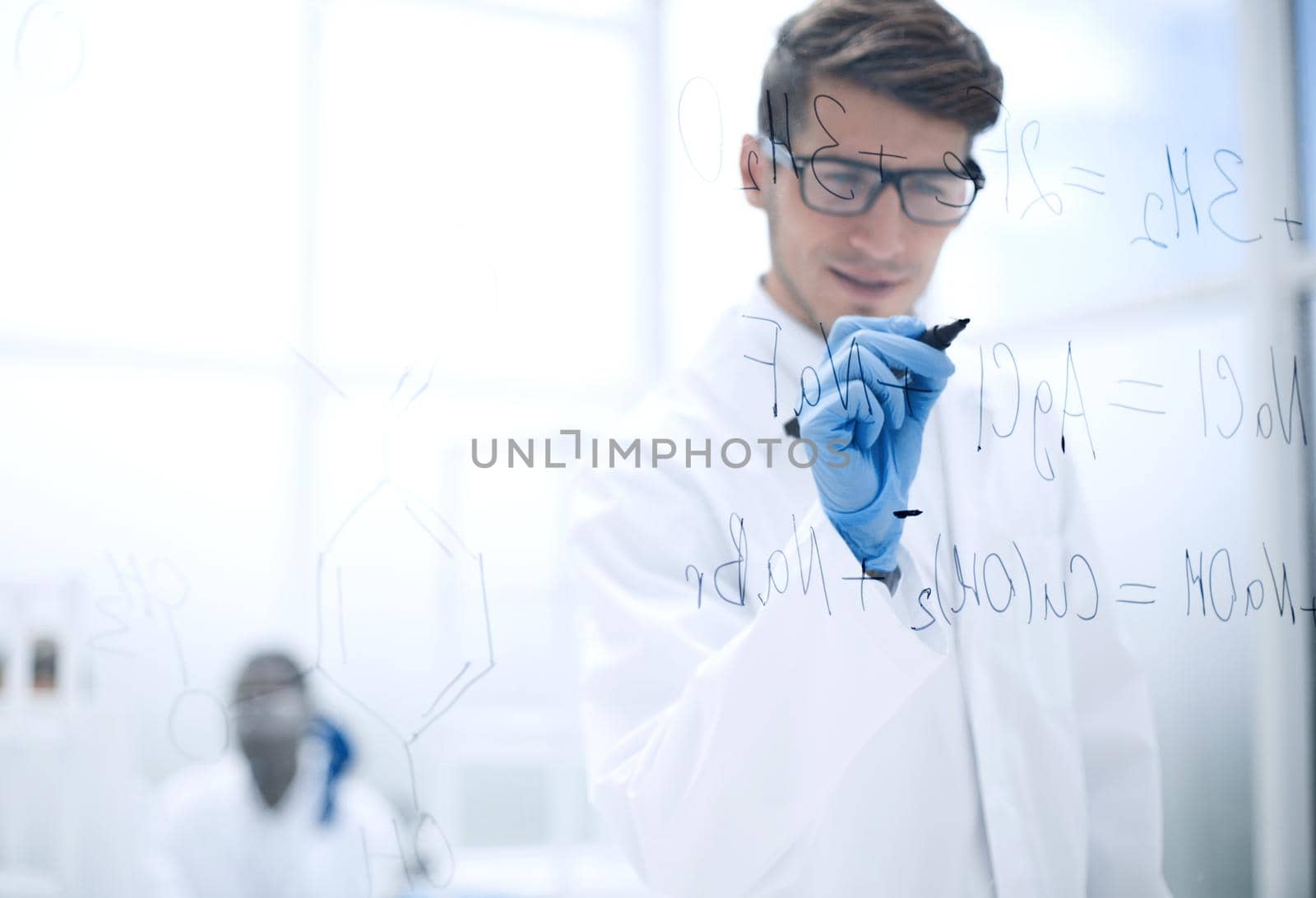 young scientist making notes on the glass Board at the time of the experiment.photo with copy space