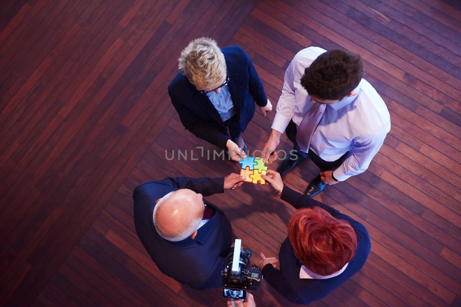 business people group assembling jigsaw puzzle and represent team support and help concept, top view perspective at modern bright office interior