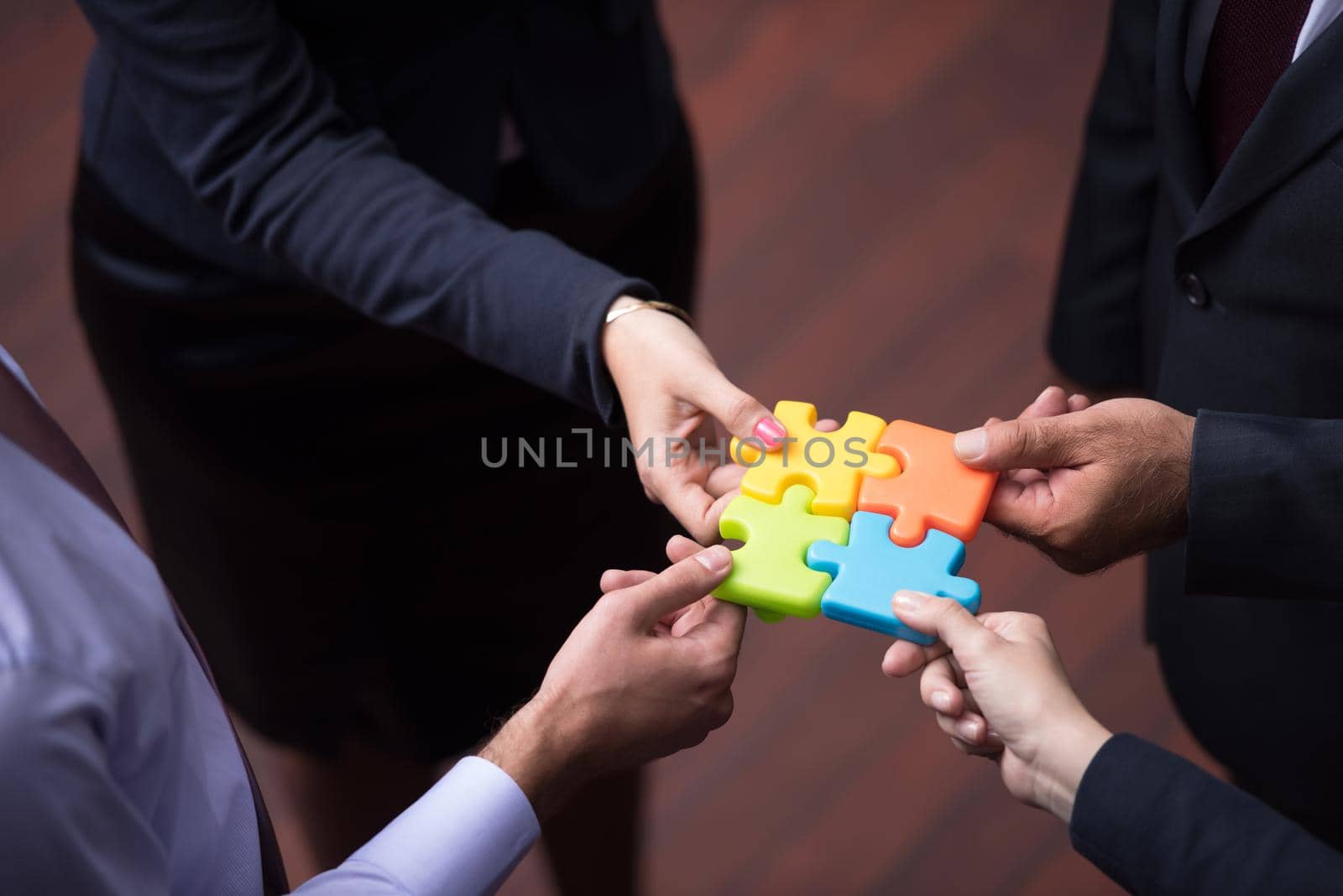 top view of business people group assembling jigsaw puzzle by dotshock