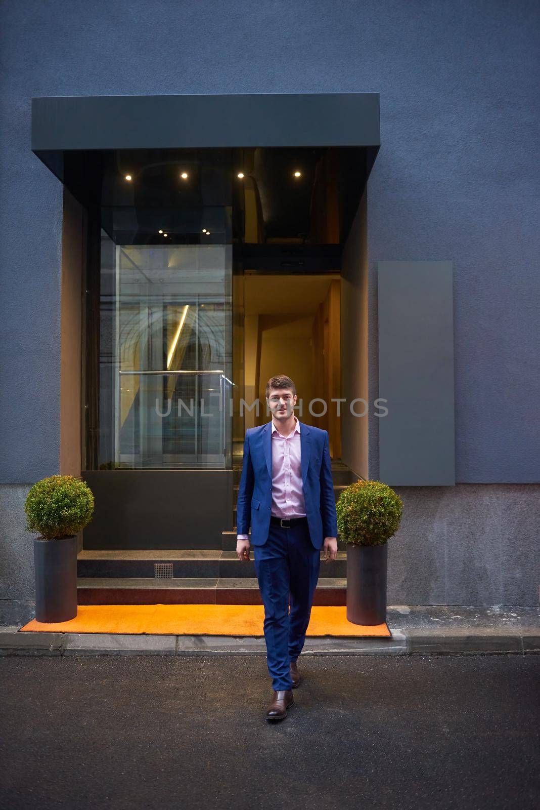 Young business man entering city  hotel, looking for room, holding suitcases while walking on street