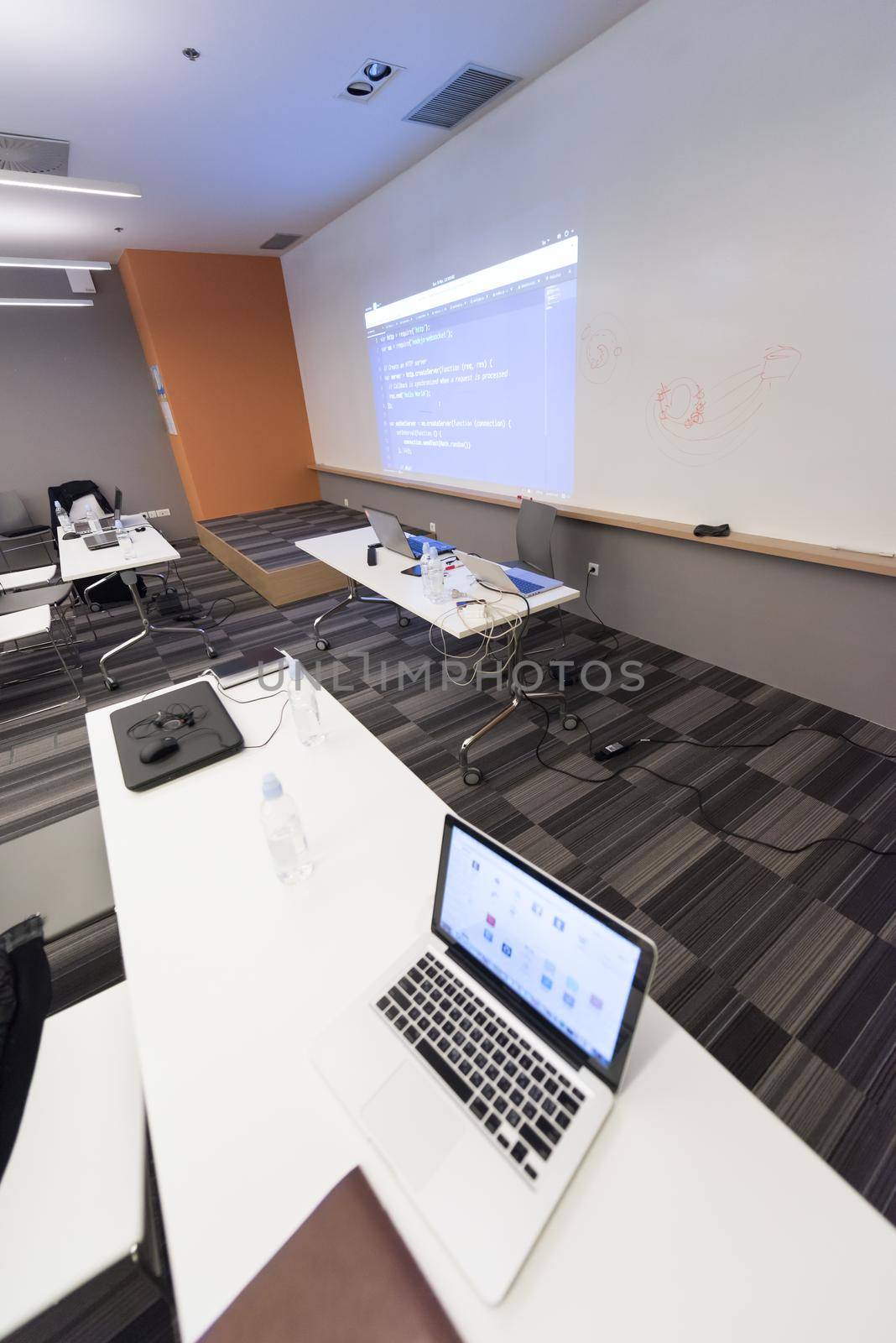 empty it classroom with program code on projector screen and modern laptop computers on table