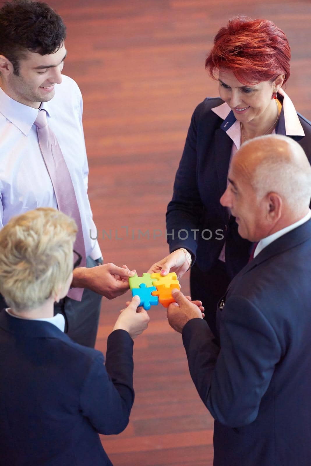 business people group assembling jigsaw puzzle and represent team support and help concept, top view perspective at modern bright office interior