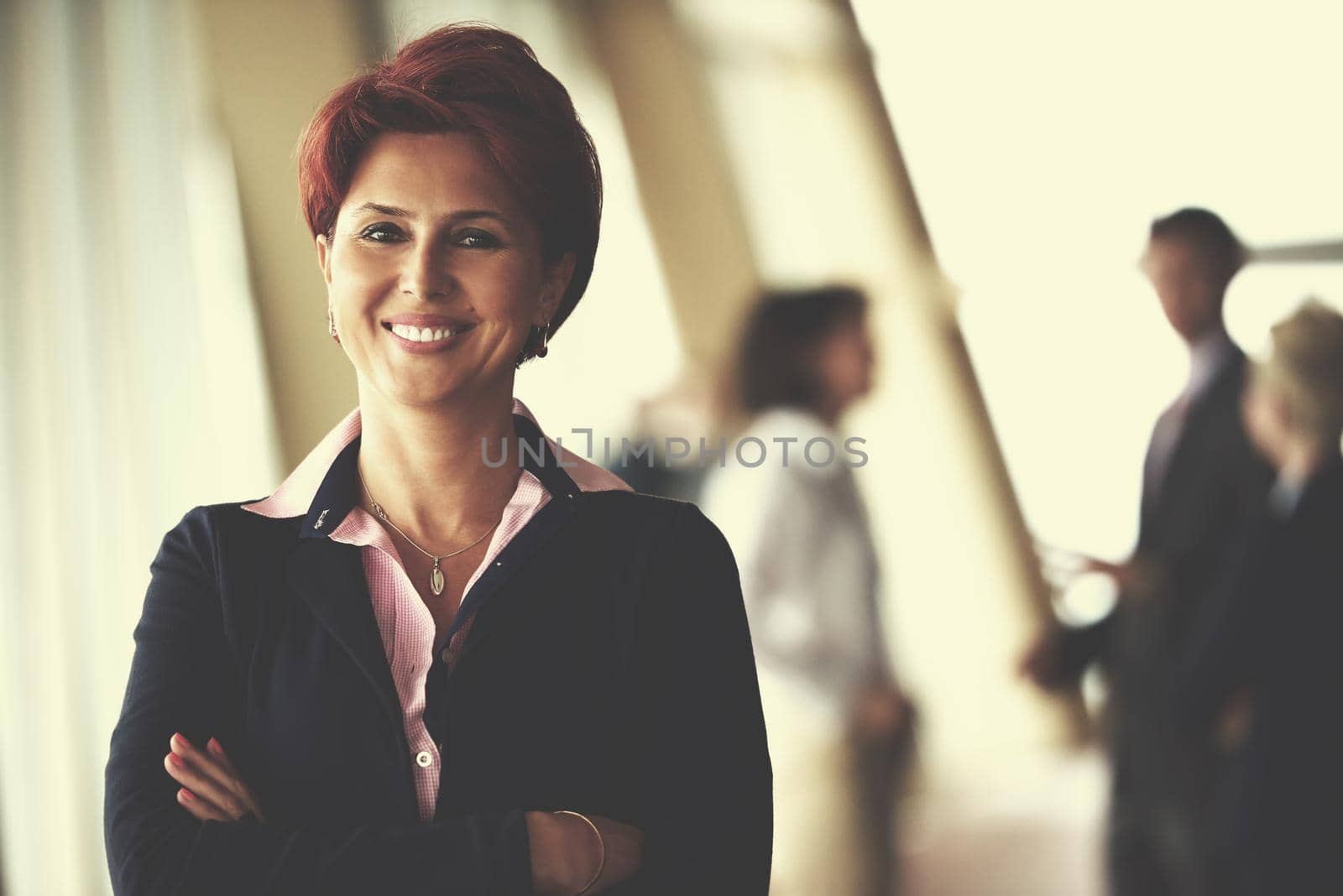 Smilling young business woman in front her team blured in background. Group of young business people. Modern bright  startup office interior.