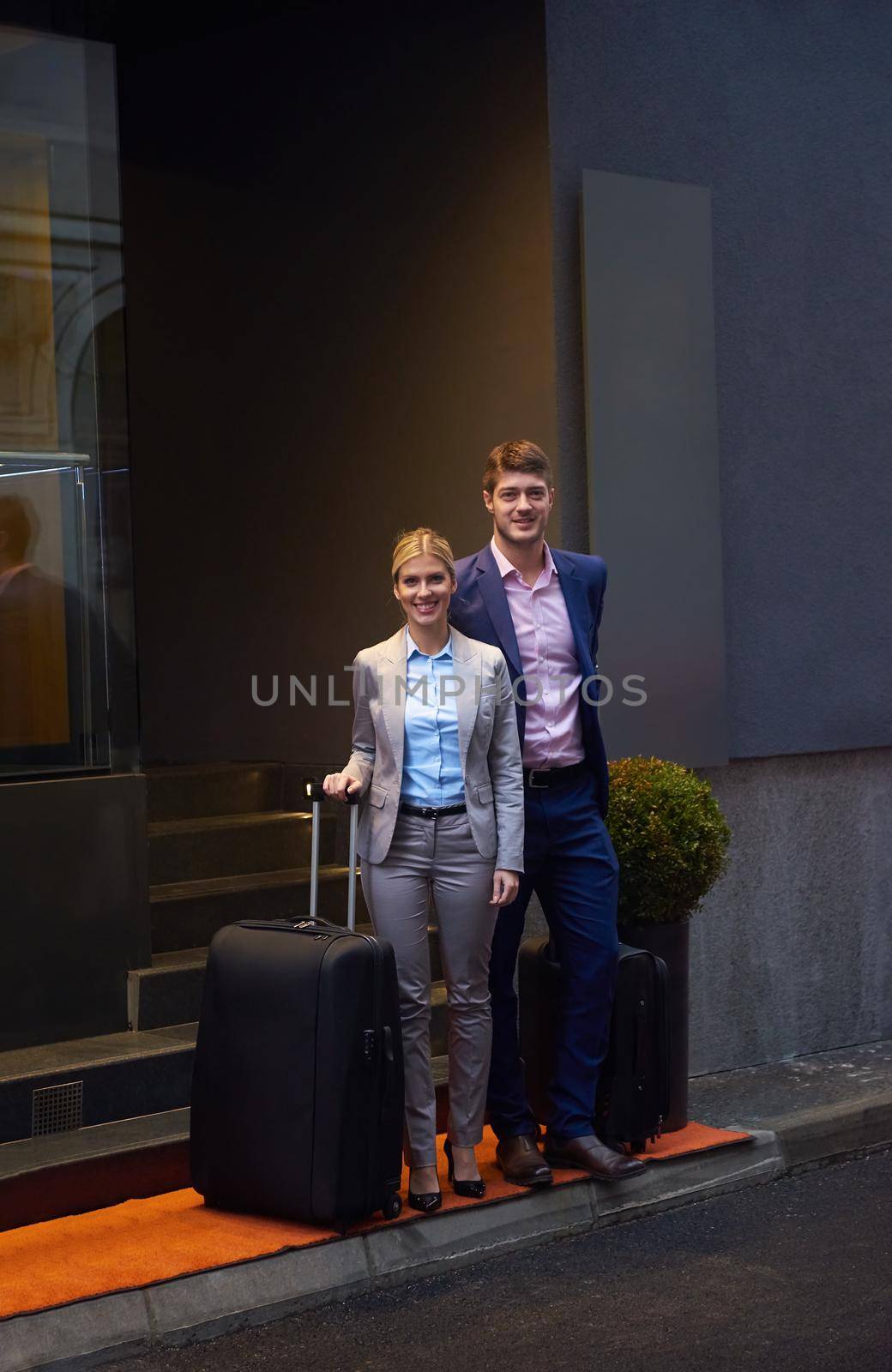 Young business people couple entering city  hotel, looking for room, holding suitcases while walking on street