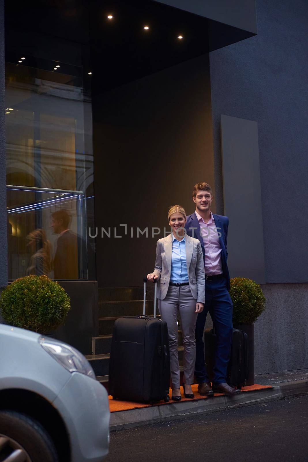 Young business people couple entering city  hotel, looking for room, holding suitcases while walking on street