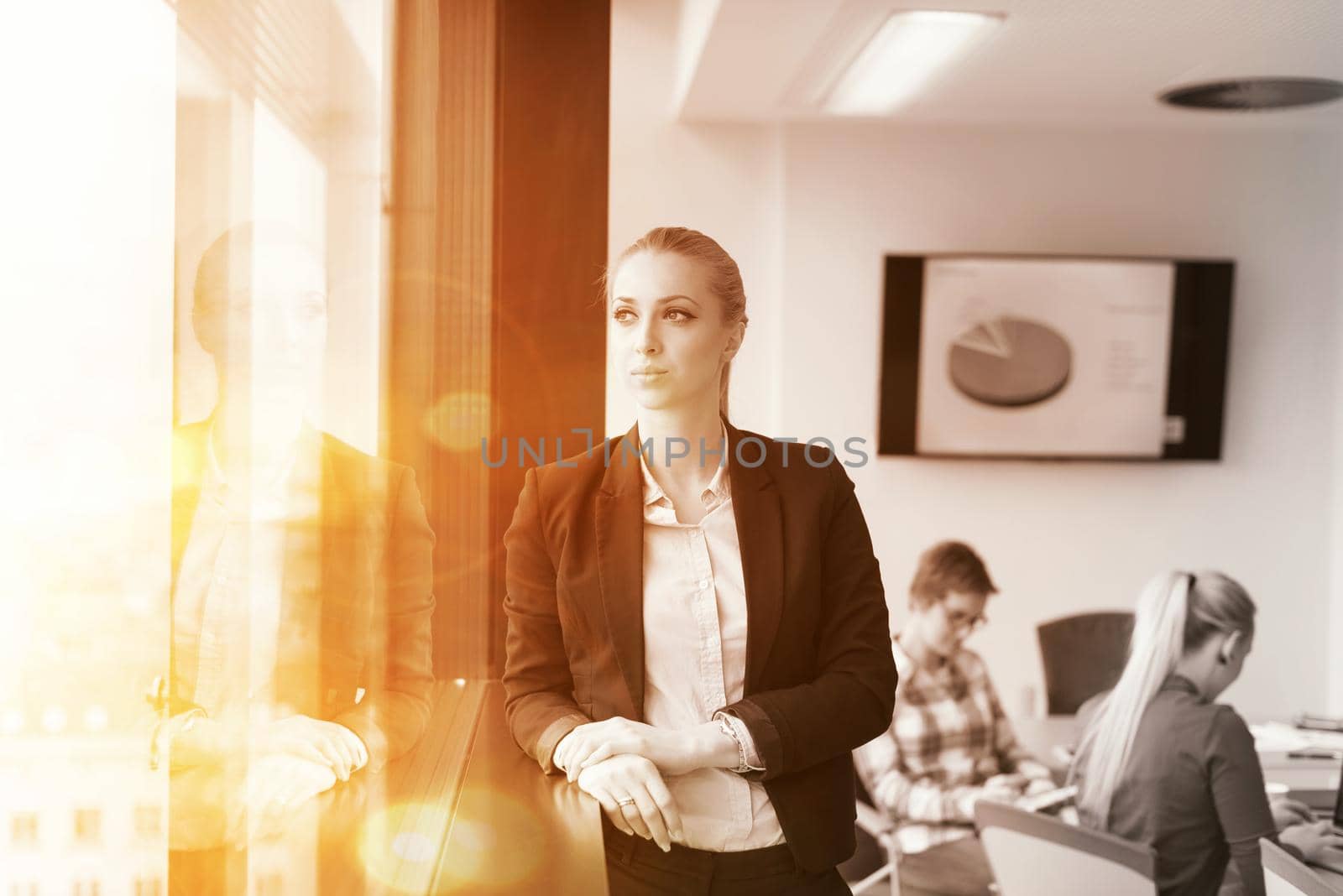 portrait of young business woman at office with team on meeting in background by dotshock