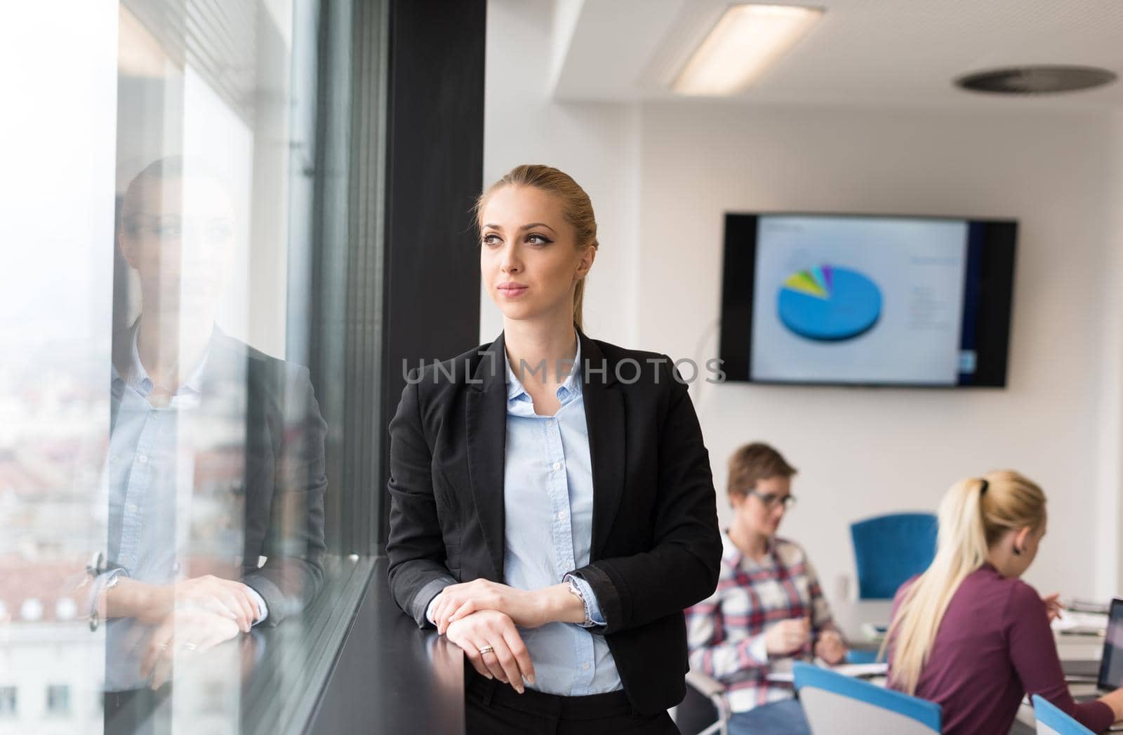 portrait of young business woman at modern startup office interior, team in meeting group in background