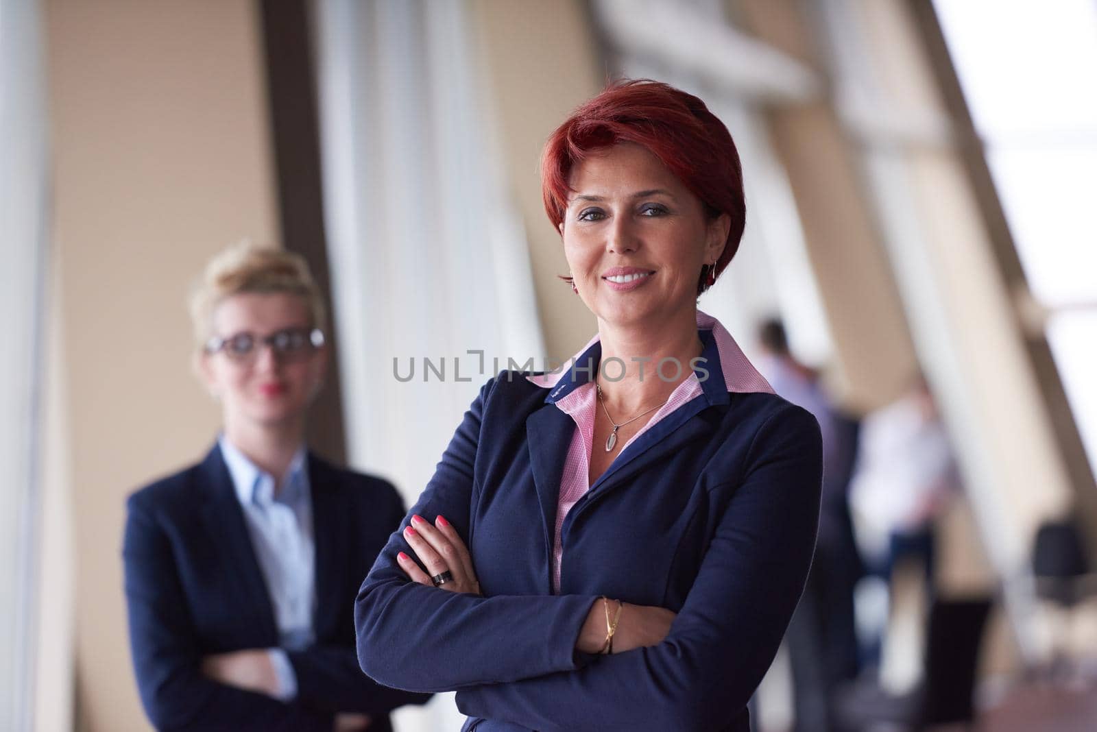 portrait  of two corporate business woman at modern bright office interior standing in group as team