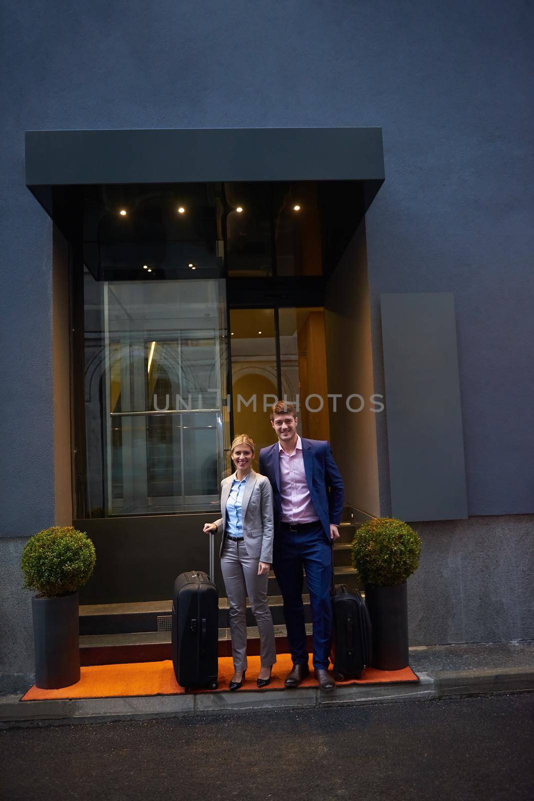 Young business people couple entering city  hotel, looking for room, holding suitcases while walking on street