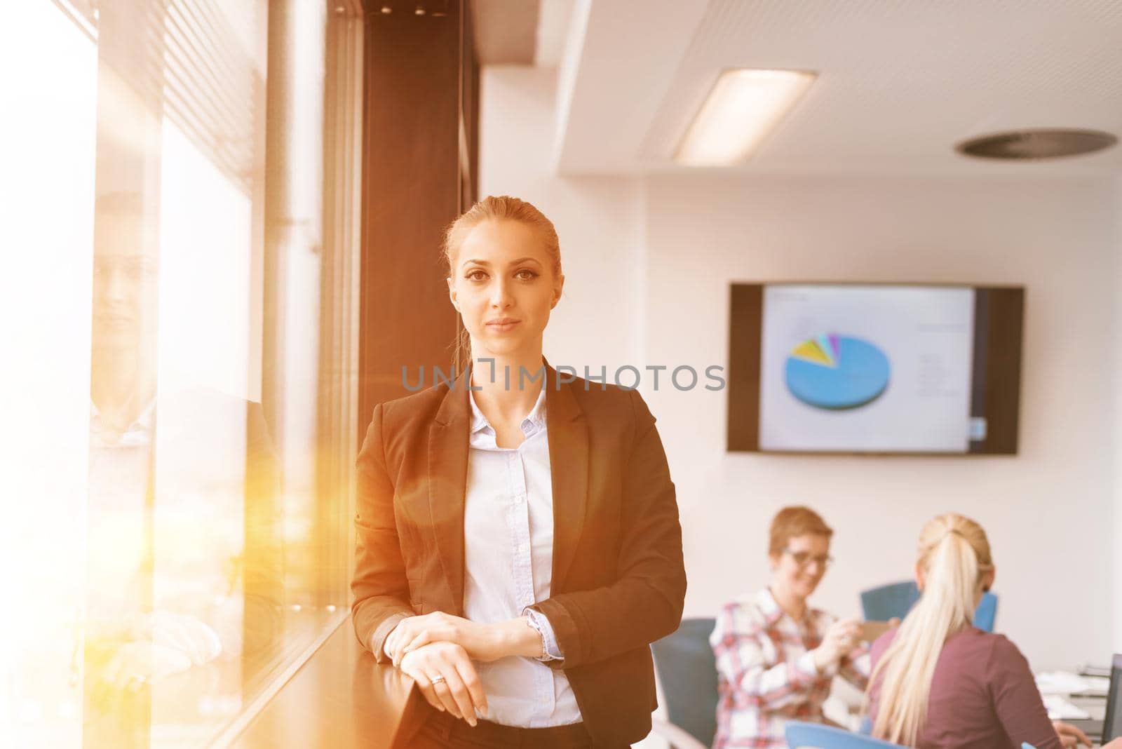 portrait of young business woman at office with team on meeting in background by dotshock