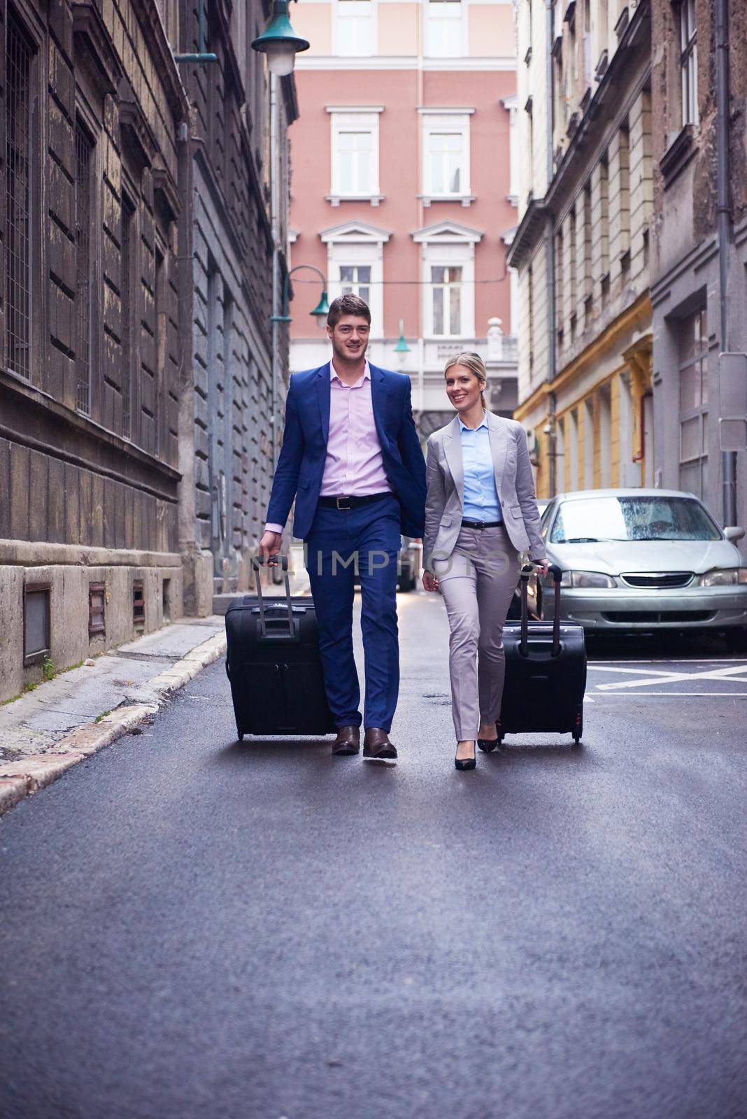 Young business people couple entering city  hotel, looking for room, holding suitcases while walking on street