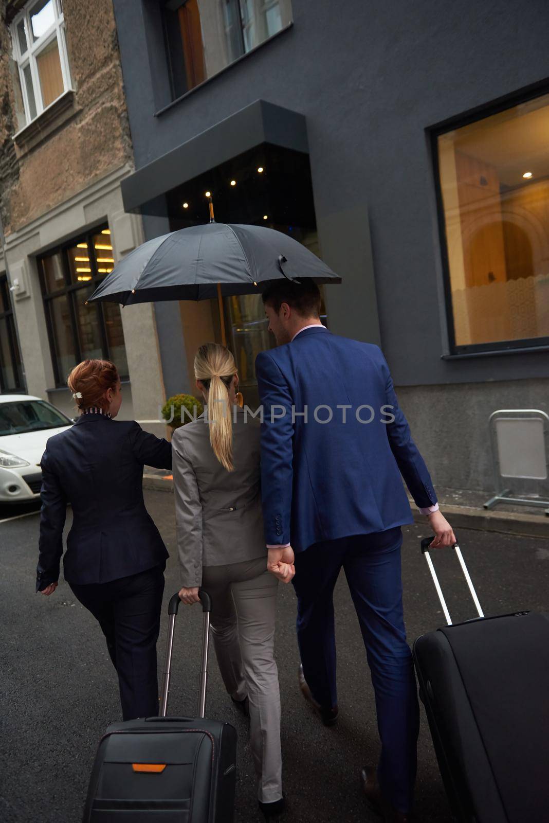 Young business people couple entering city  hotel, looking for room, holding suitcases while walking on street