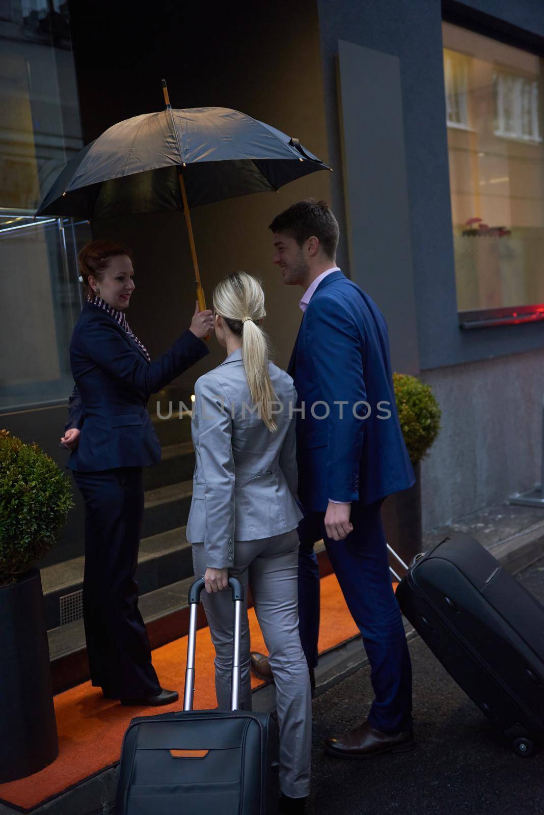 Young business people couple entering city  hotel, looking for room, holding suitcases while walking on street