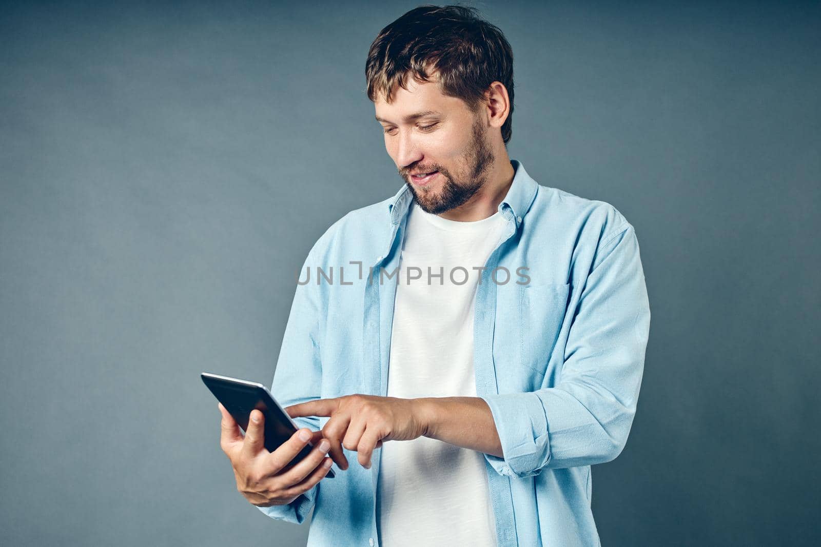 A middle-aged white Caucasian man holds a tablet in his hand and looks at a mobile application. by SergeyPakulin