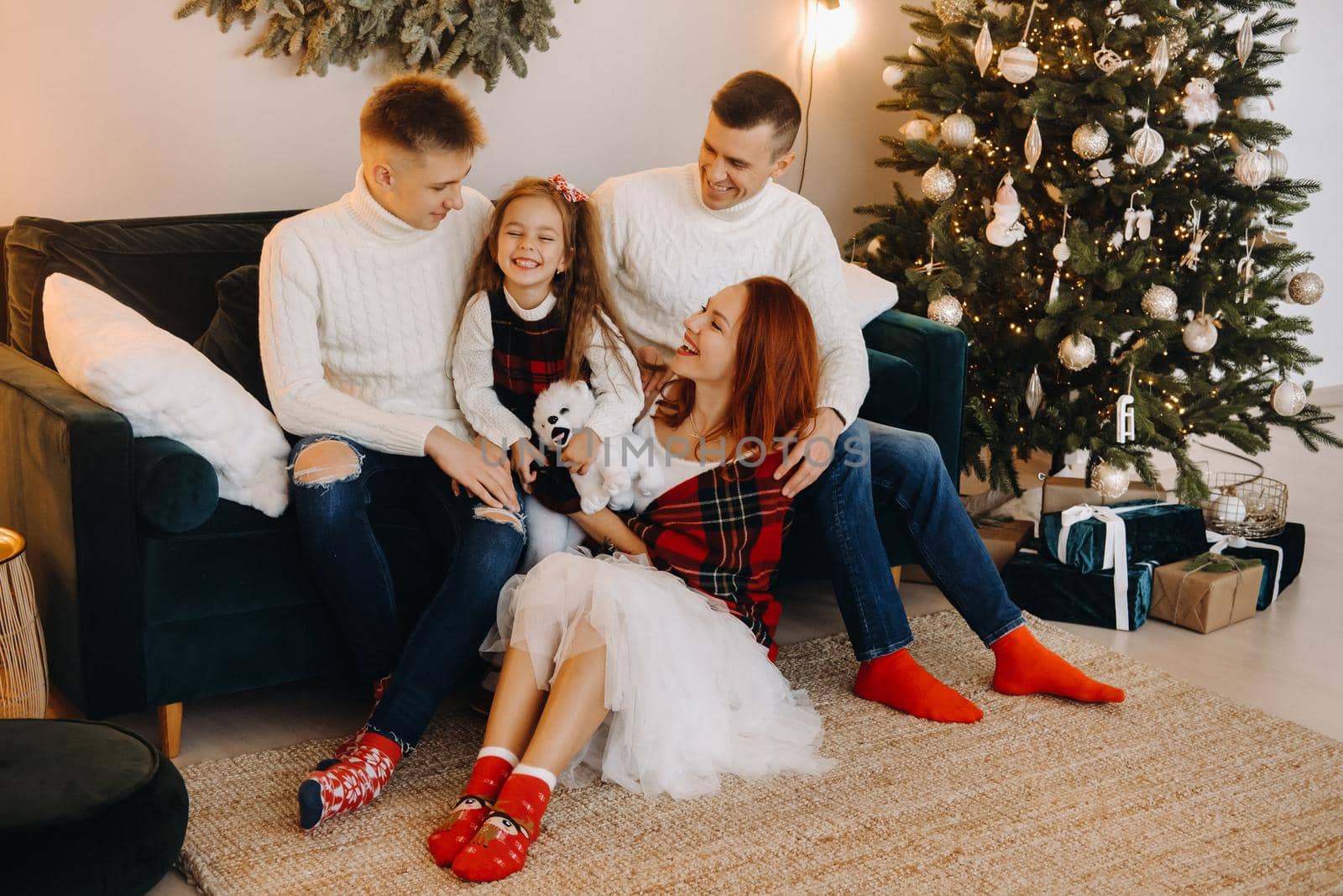 Close-up portrait of a happy family sitting on a sofa near a Christmas tree celebrating a holiday.