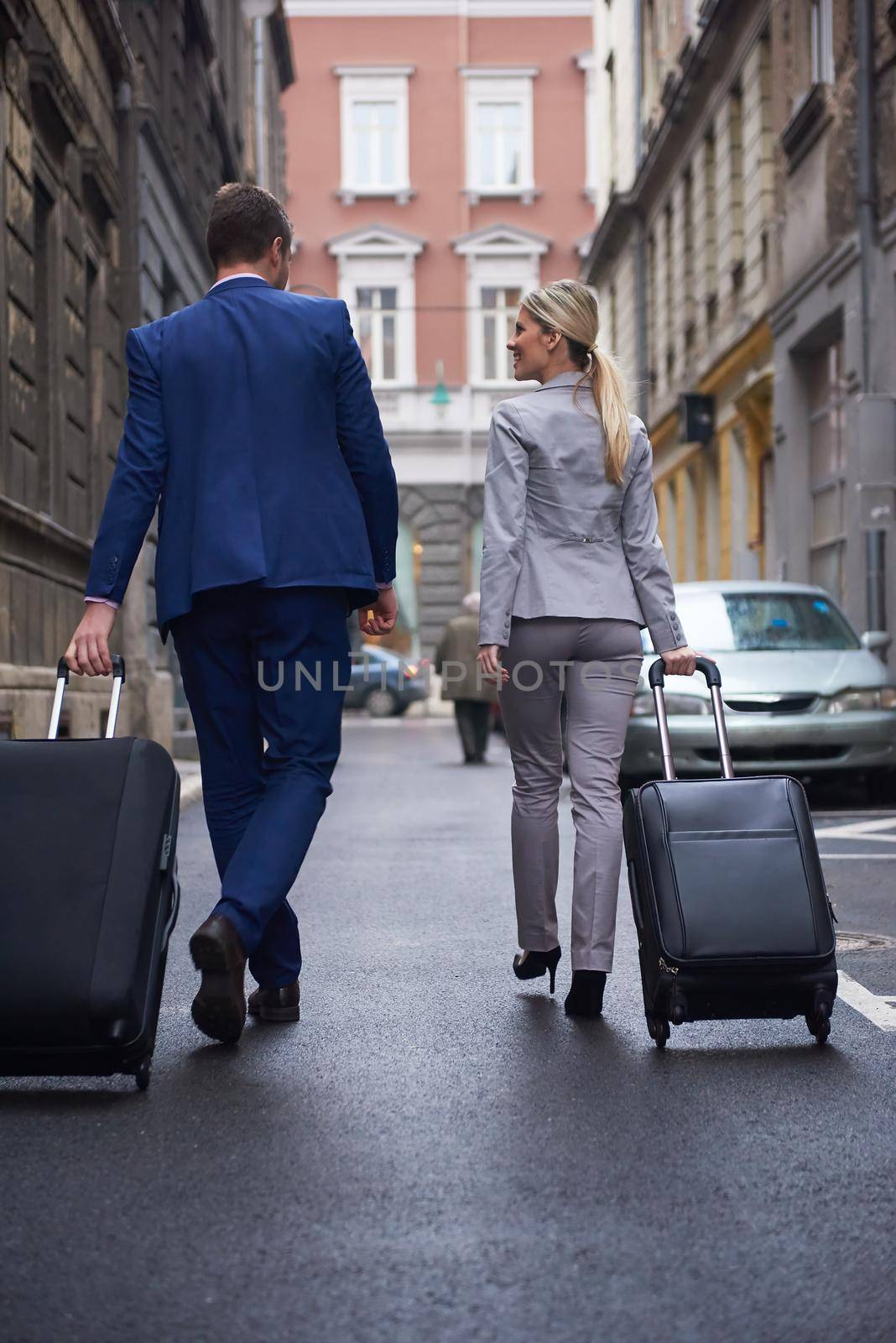 Young business people couple entering city  hotel, looking for room, holding suitcases while walking on street