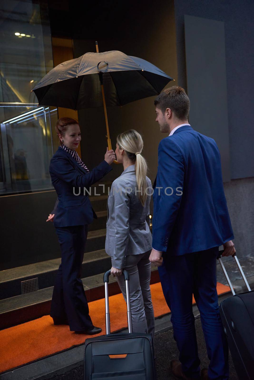 Young business people couple entering city  hotel, looking for room, holding suitcases while walking on street