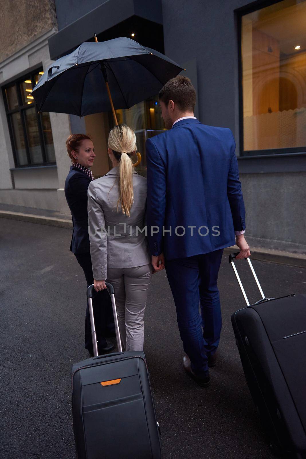 Young business people couple entering city  hotel, looking for room, holding suitcases while walking on street