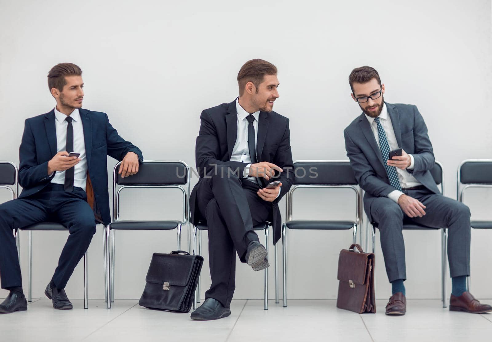 employees with smartphones sitting in the office hallway by asdf