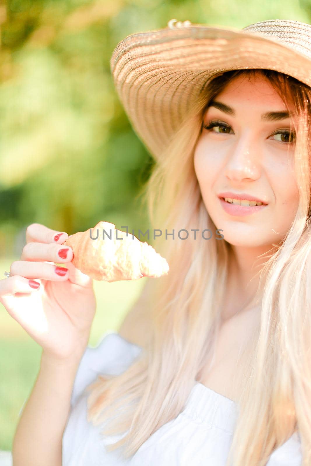 Portrait of young pretty caucasian girl in hat keeping croissant. Concept of beauty, female person and bakery products.