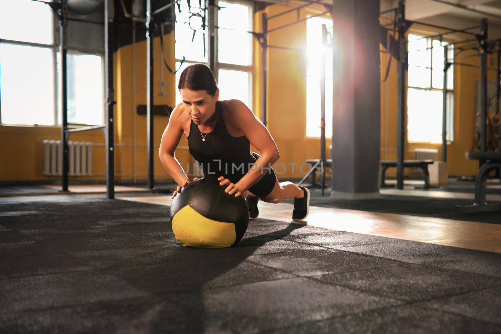 Fit and muscular woman exercising with medicine ball at gym