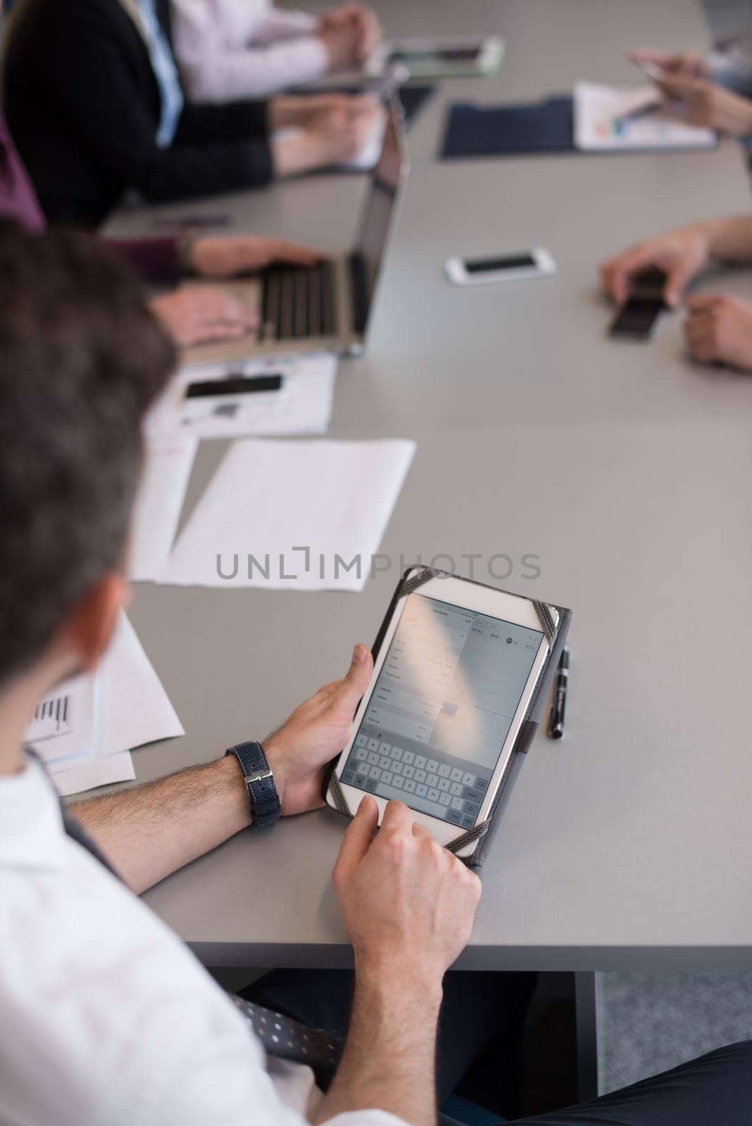 close up of  businessman hands  using tablet, people group in office meeting  room blurred in backgronud