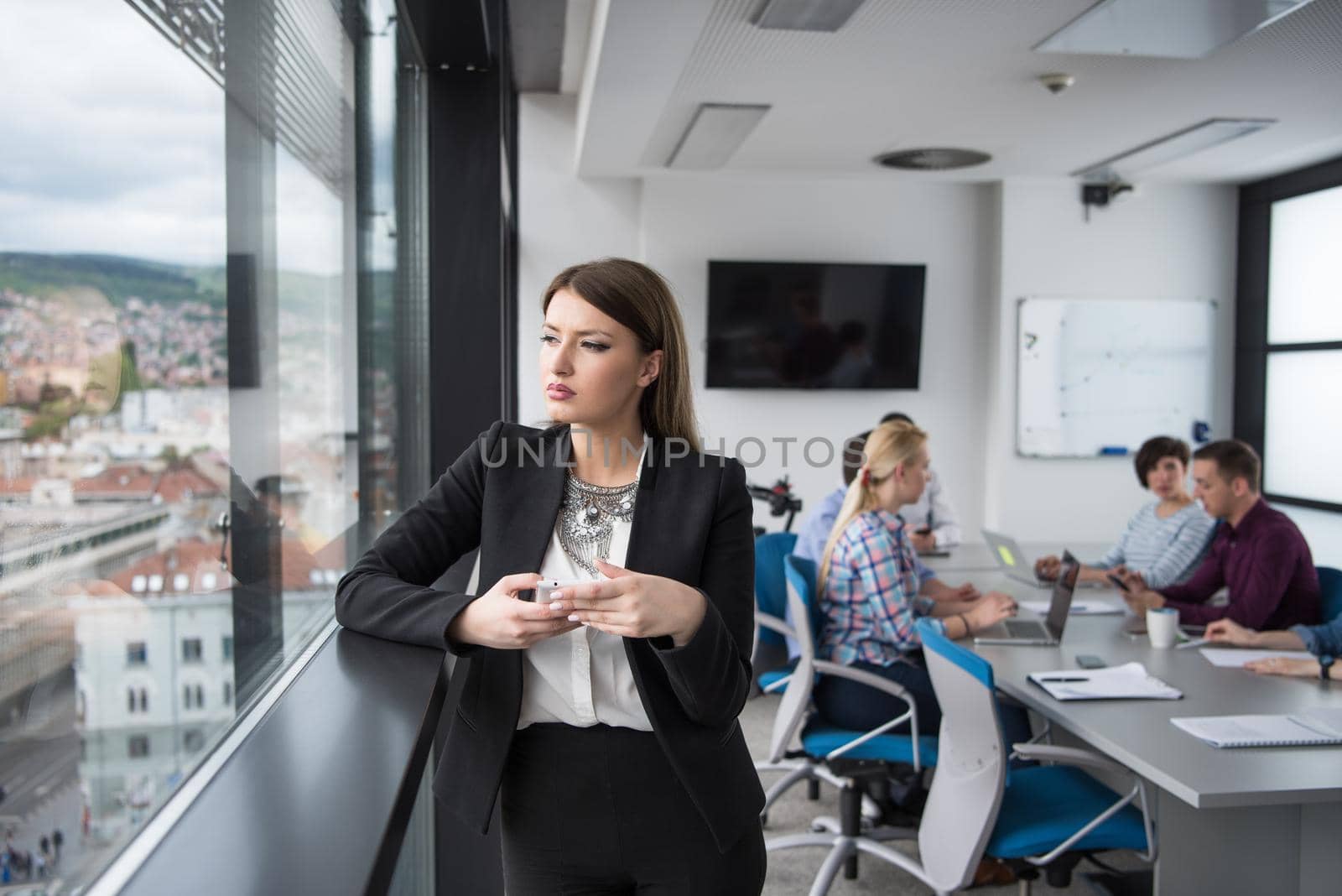 businesswoman speeking on phone beside window of modern office