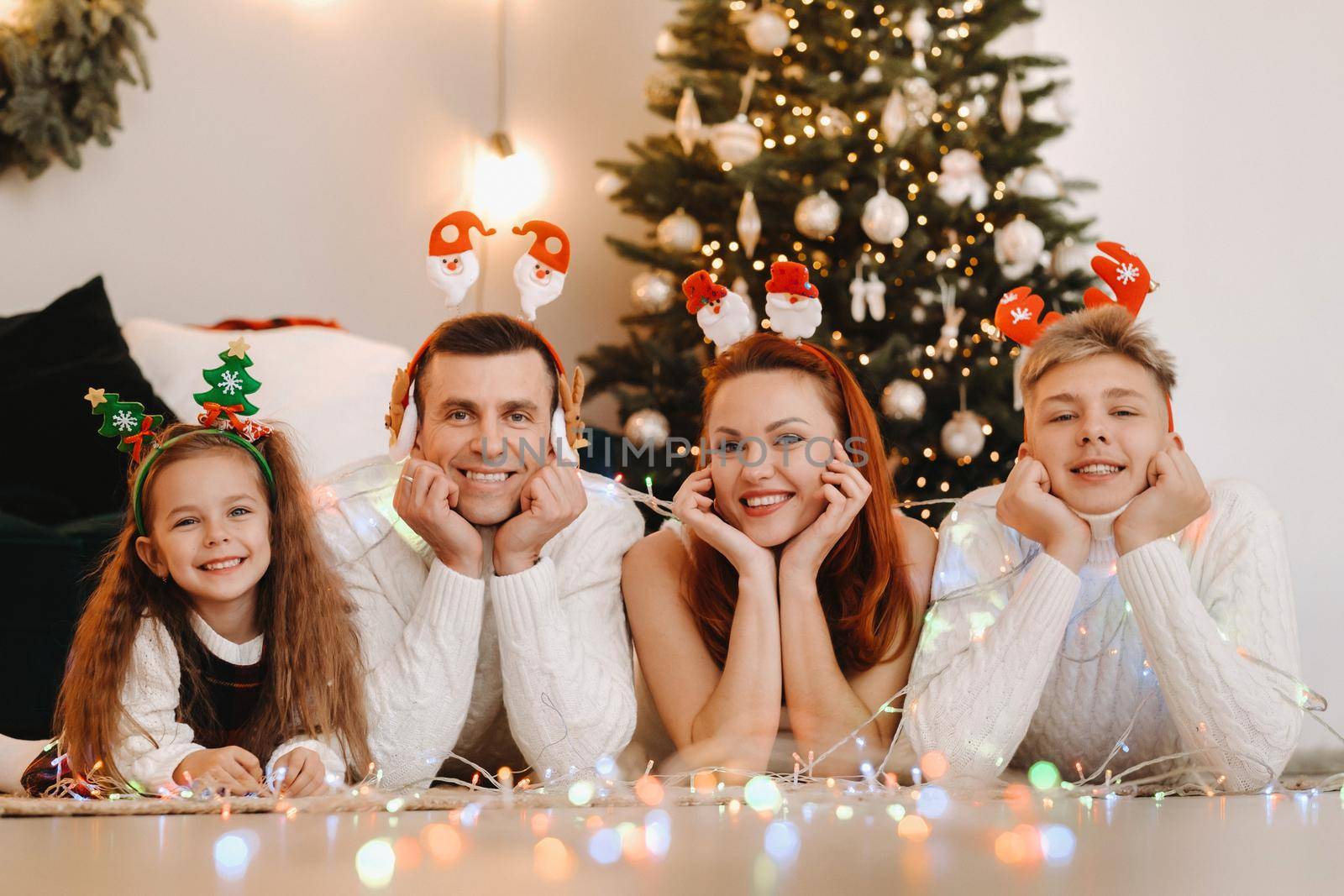 Close-up portrait of a happy family lying near a Christmas tree celebrating a holiday.