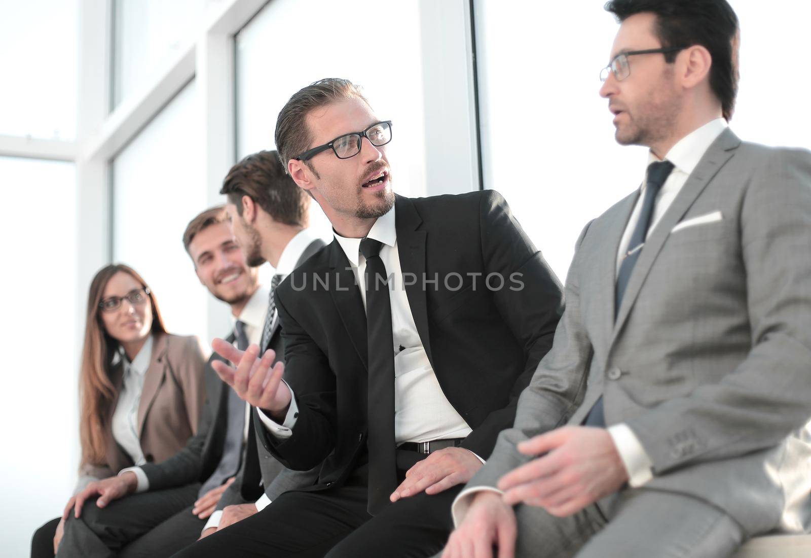 confident qualified young manager sitting with his colleagues at a seminar