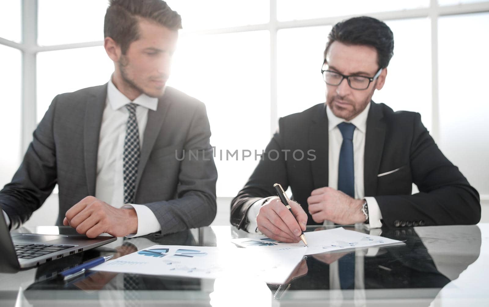 two businessmen discuss financial documents. office weekdays