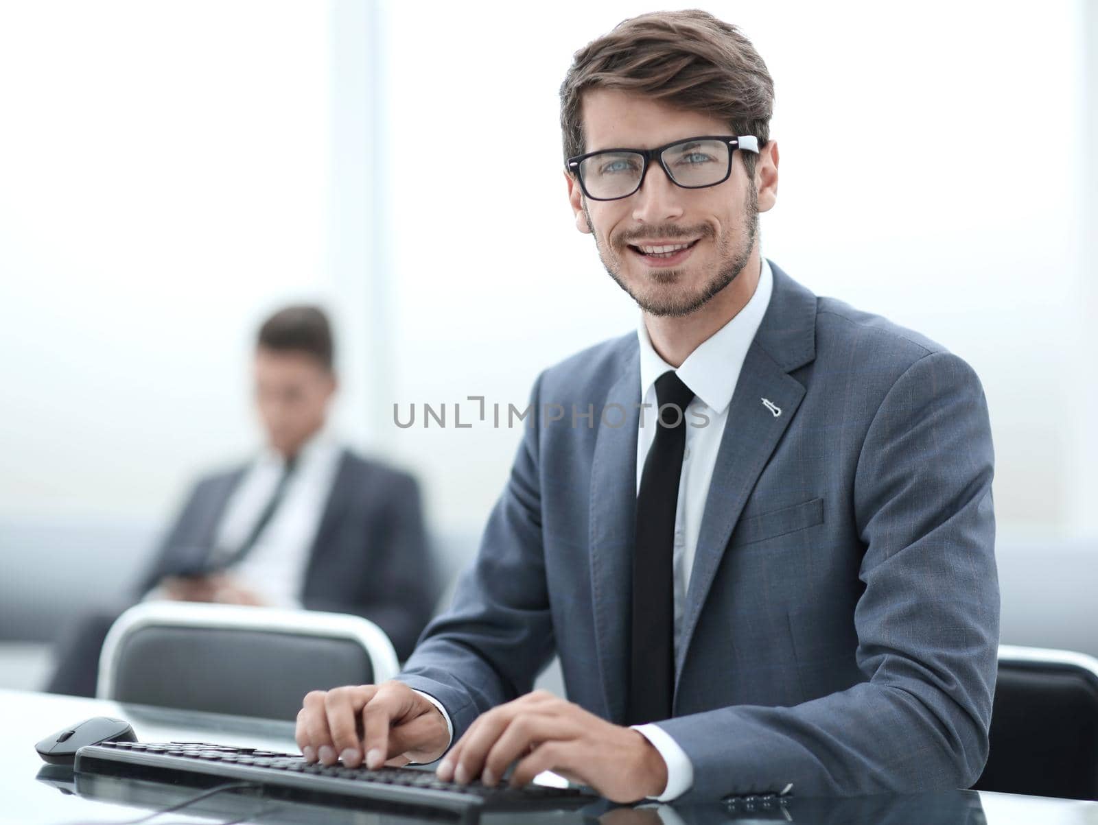 Happy young man, wearing glasses and smiling, as he works on his laptop to get all his business done early in the morning