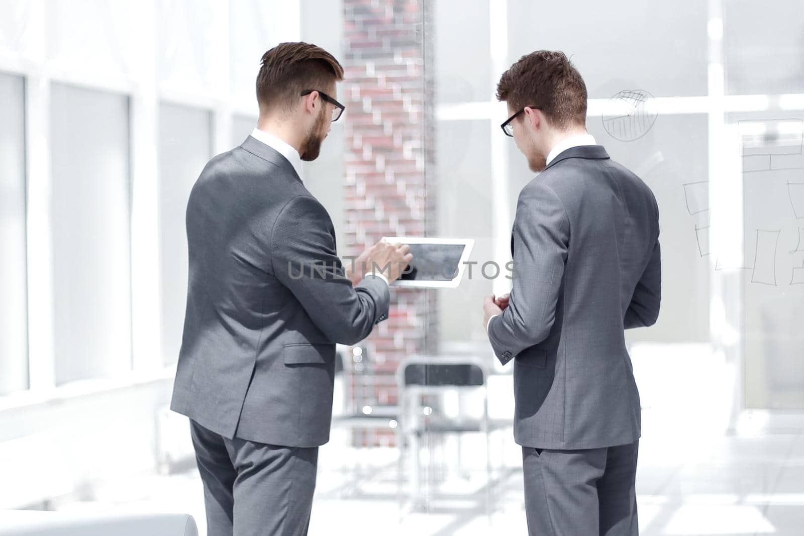 employees discuss information using a digital tablet. photo from copies of space