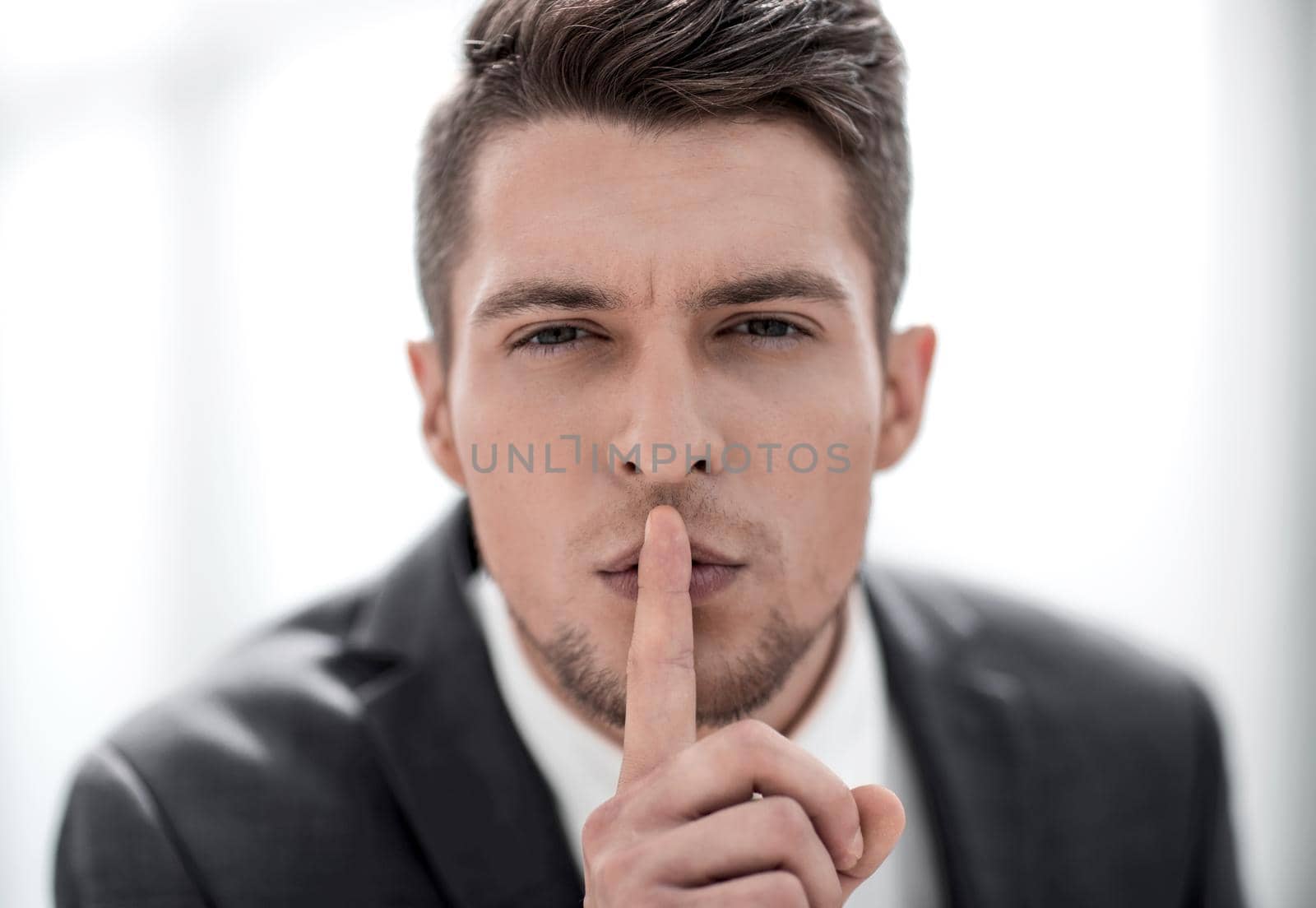 Portrait businessman showing silence gesture. Silence and secrecy concept