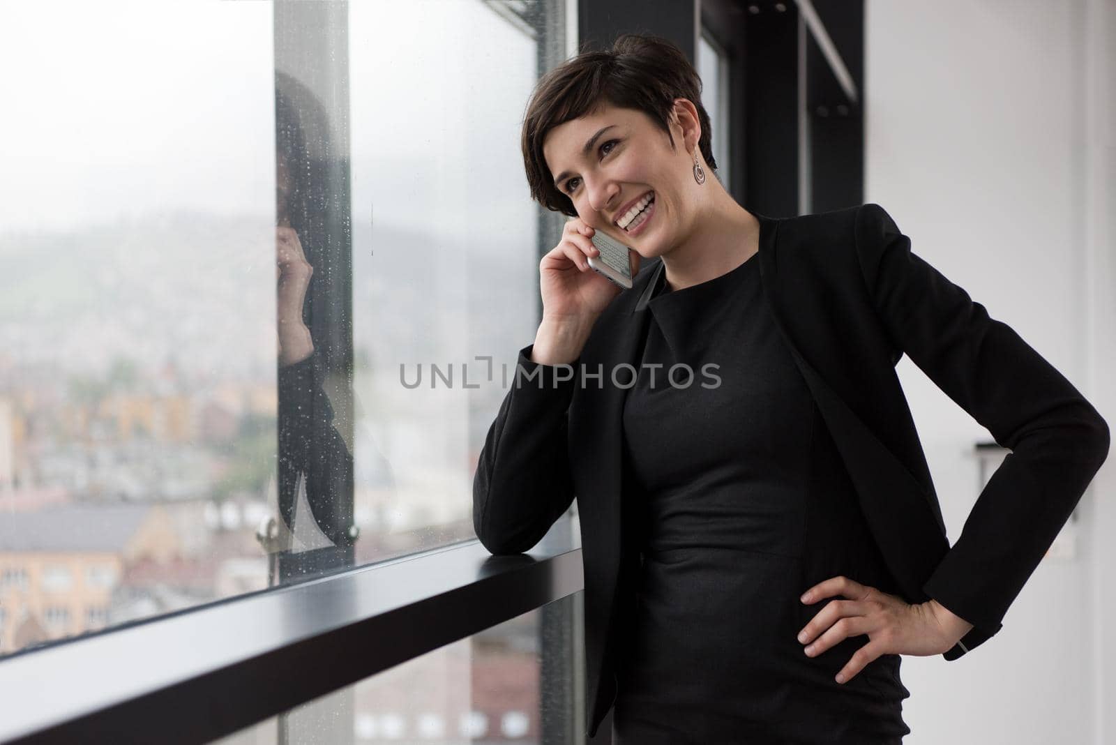Elegant Woman Using Mobile Phone by window in office building by dotshock