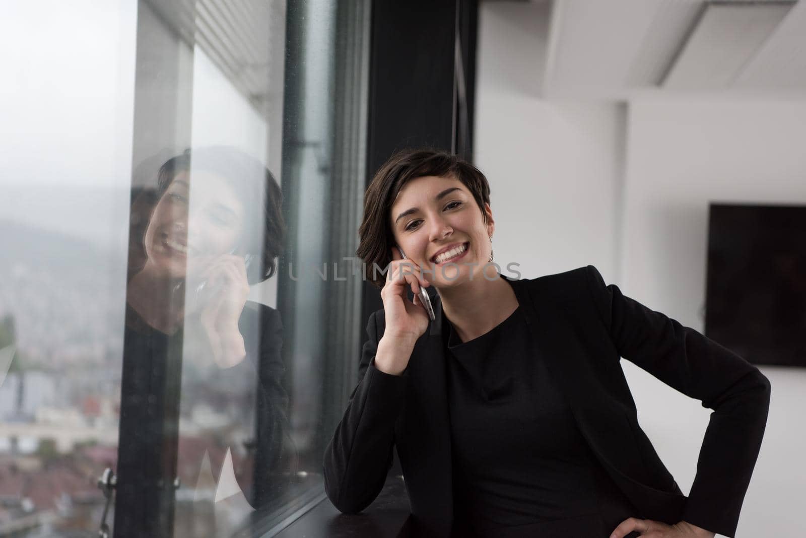 Elegant Woman Using Mobile Phone by window in office building by dotshock