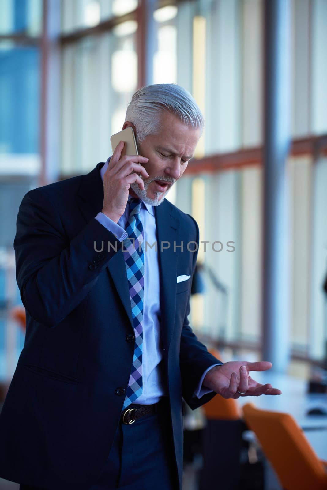 senior business man talk on mobile phone  at modern bright office interior