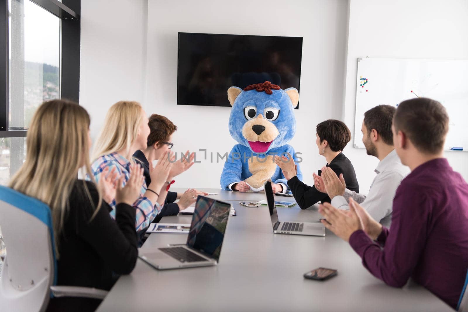 Boss dresed as teddy bear having fun with bussines people in modern corporate office