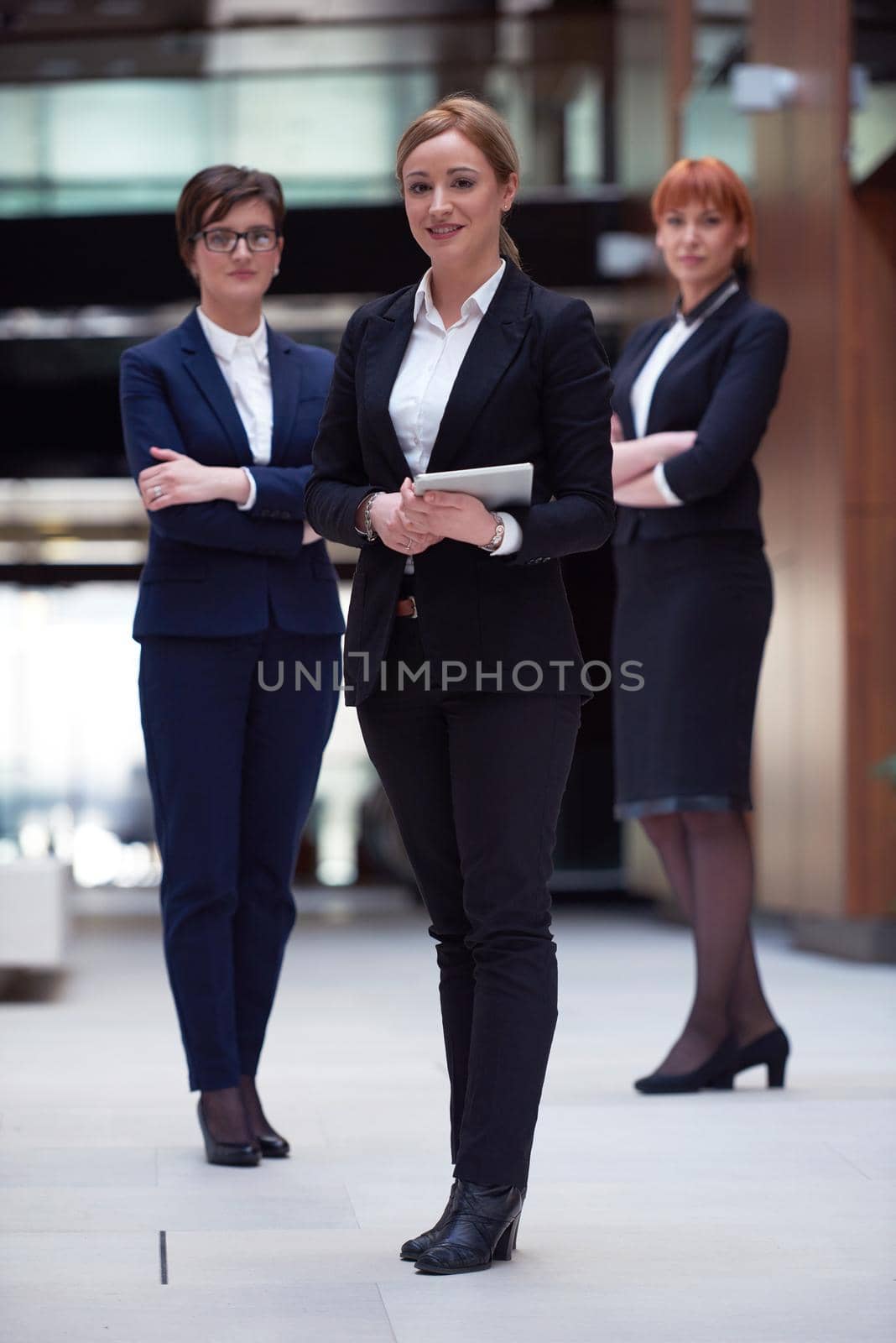 young business woman group,  team standing in modern bright office and working on tablet computer